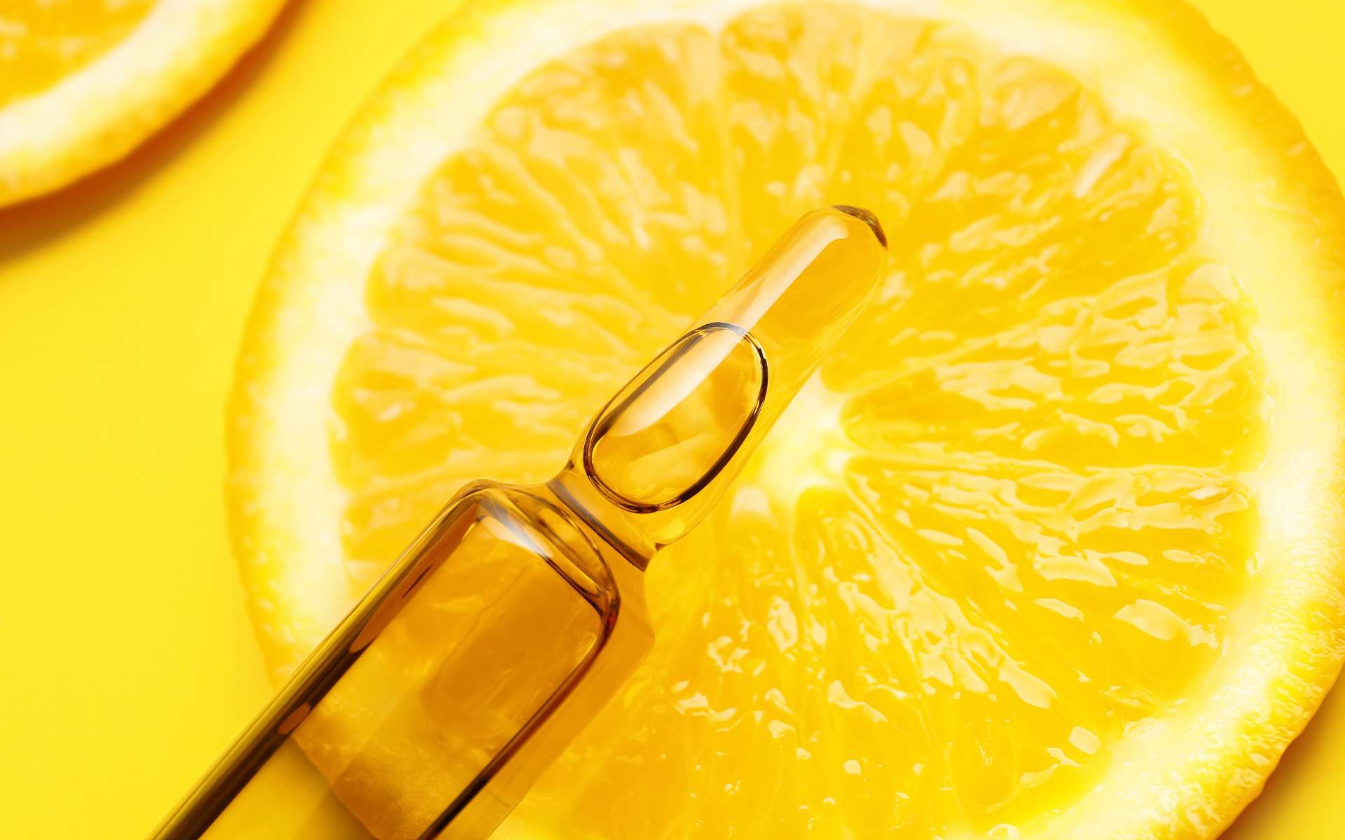 Tranche d'orange avec une pipette dessus sur fond jaune