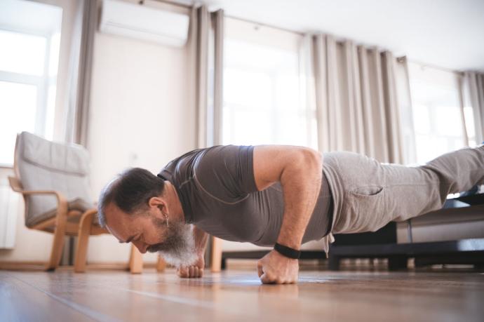 Homme senior habillé en gris avec barbe poivre et sel quifait des pompes