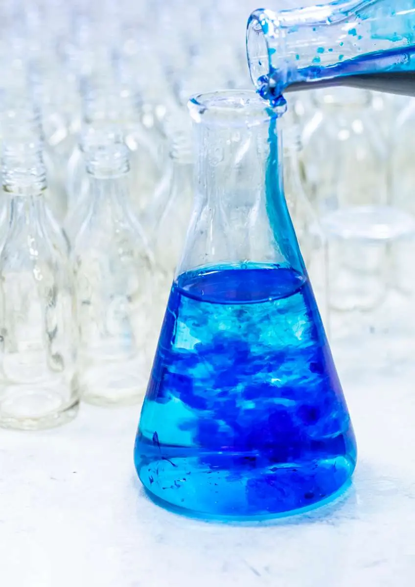 Bleu de méthylène versé dans un flacon avec des flacons vides en arrière-plan