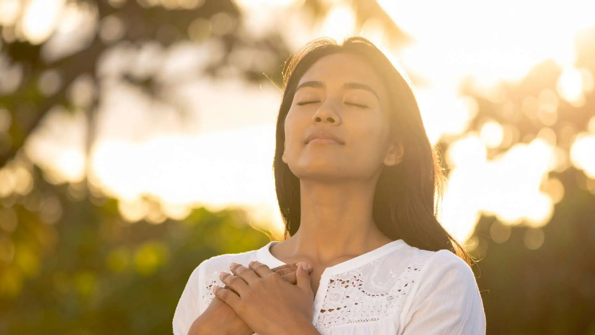 femme détendue qui respire dans la nature les yeux fermas les mains  sur son coeur