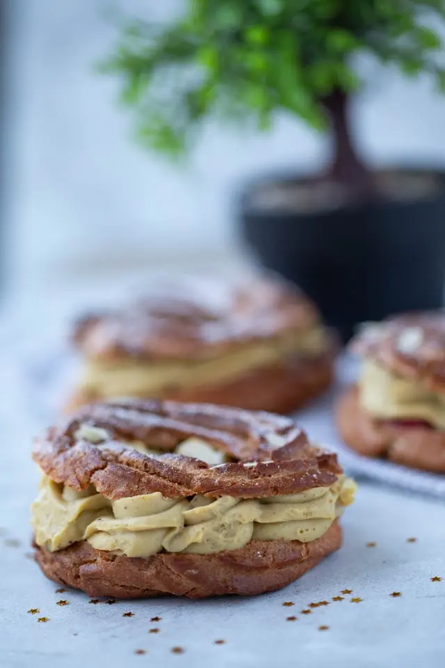 Trois gâteaux Saint-Honoré avec plante en arrière-plan
