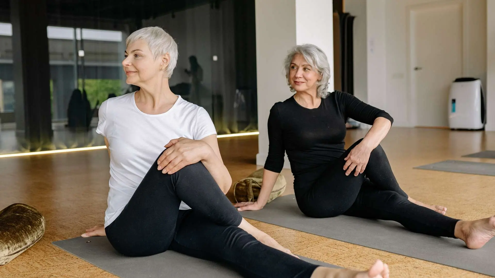 Deux femmes seniors sur tapis de yoga faisantr des exercices de pilates dans une salle